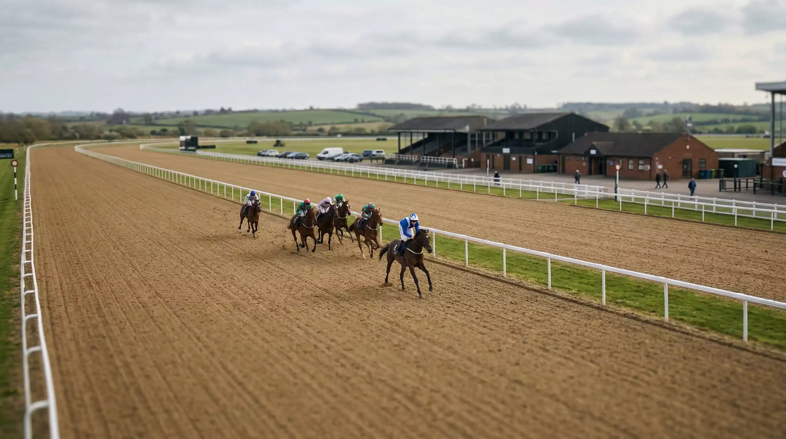 Southwell racecourse all-weather Tapeta track on a race day with horses approaching the home straight